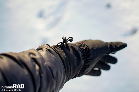 Der Gummizug am Handgelenk lässt sich auch mit Handschuhen einfach bedienen und ermöglicht ein sauberes Überziehen über den Jackenärmel – ideal gegen Kälte und Nässe.